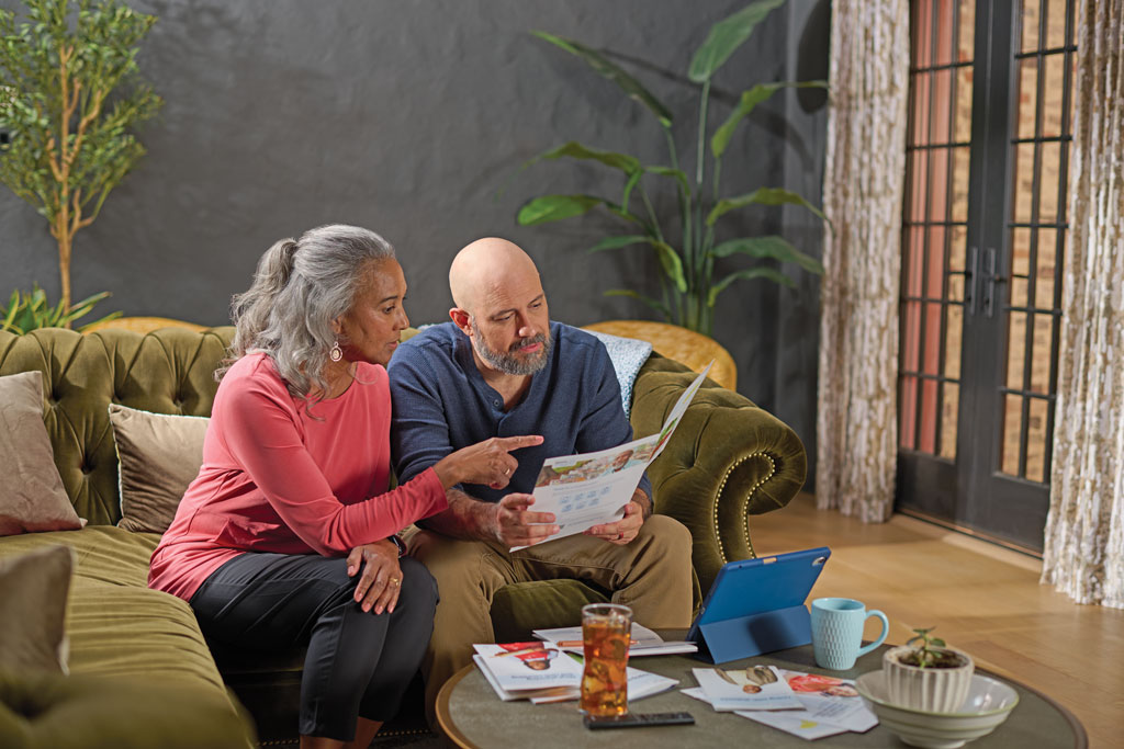 Man and woman sitting on a couch and reading through a brochure together