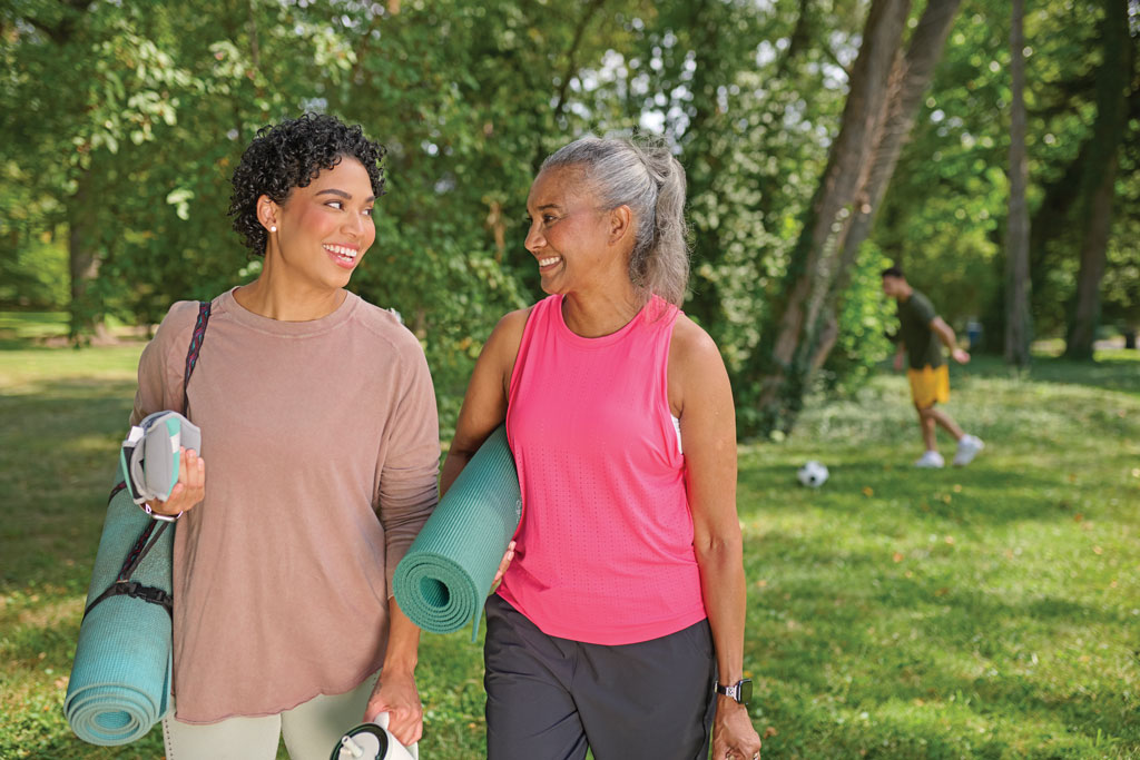 Two women walking outside and holding yoga mats