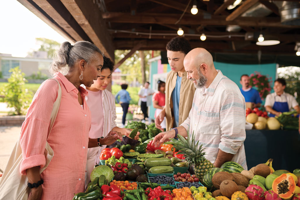 Family of four picking out produce at an outdoor market