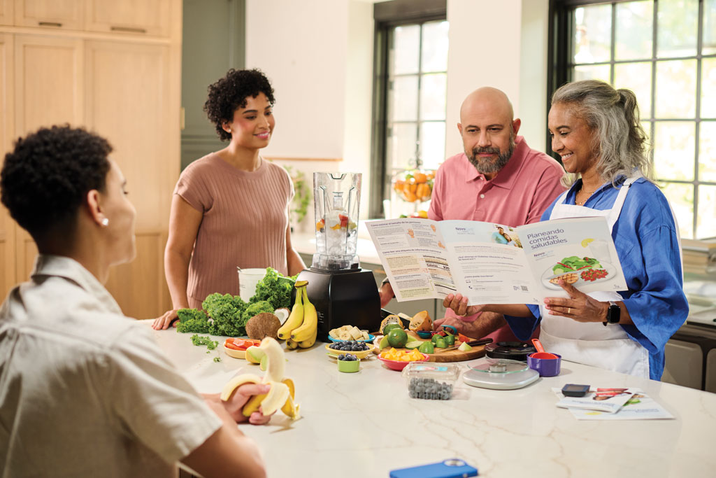 Family preparing a meal and reading a  NovoCare® brochure about healthy eating
