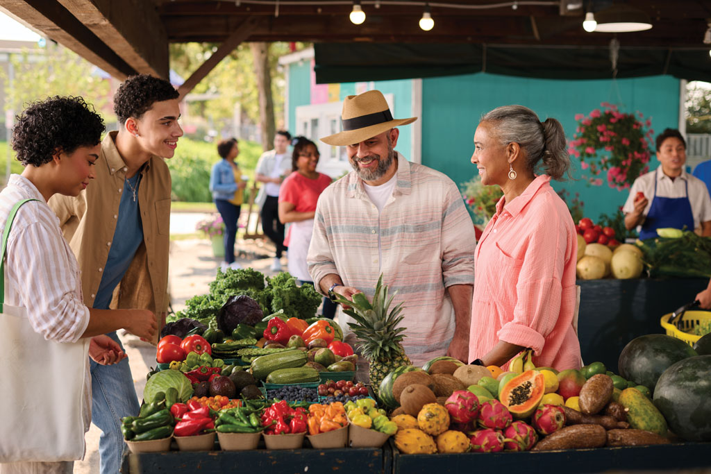 Family standing around a produce booth at an outdoor market