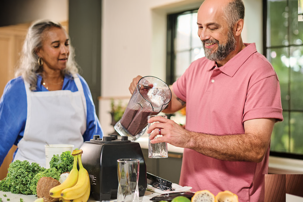 Man and woman making a smoothie and pouring it into a glass