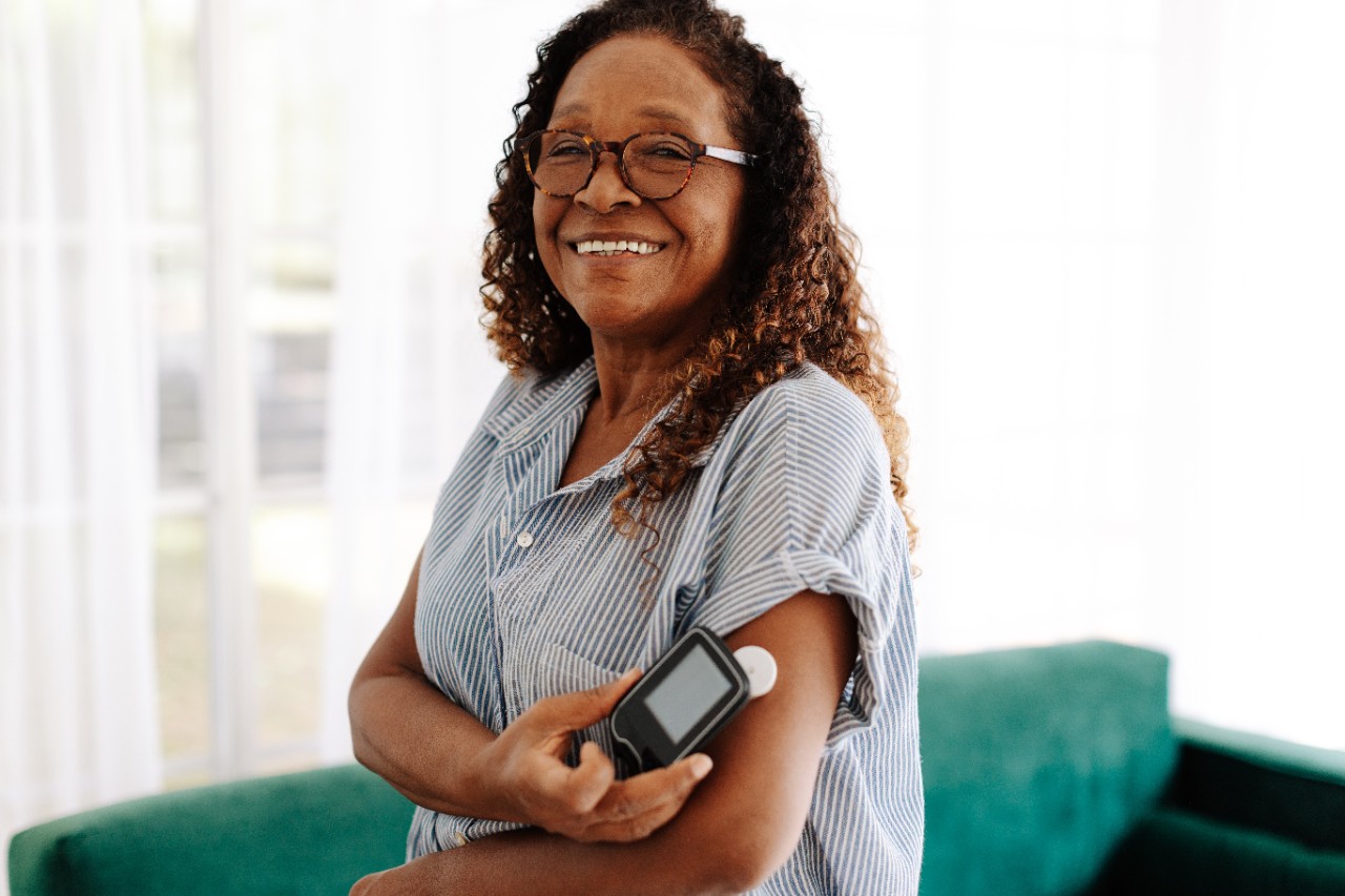 Woman smiling while using a continuous blood glucose monitor