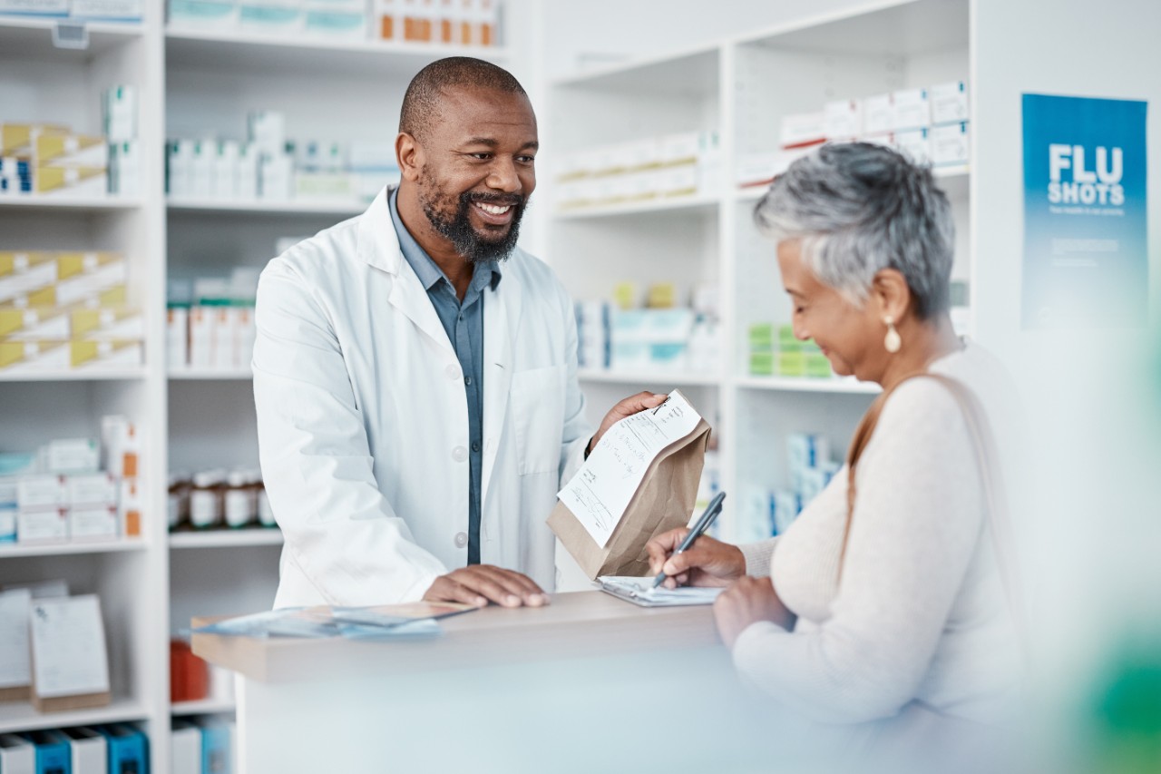 Pharmacist handing prescription medicine to patient