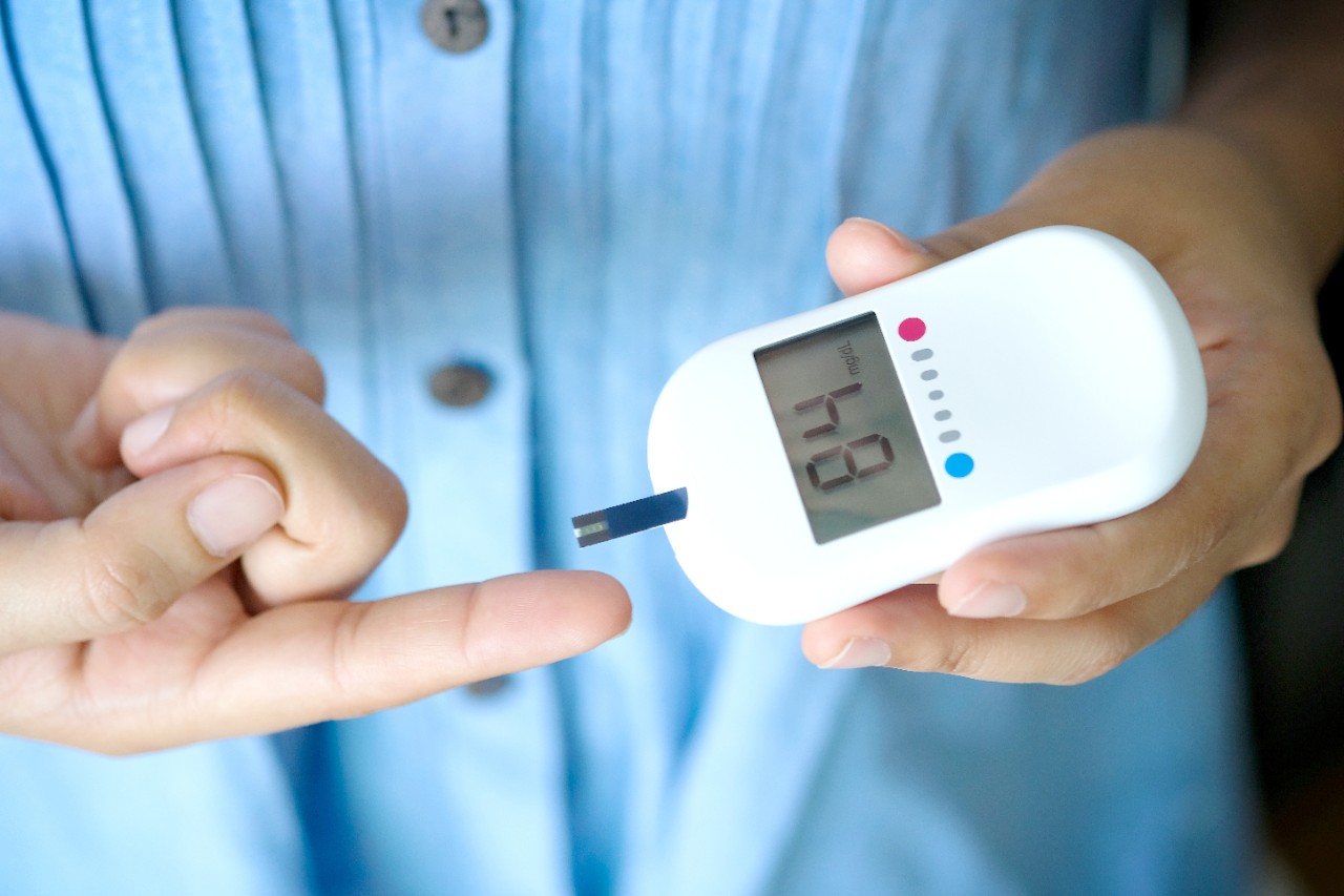 Person pricking their finger with a blood glucose monitor