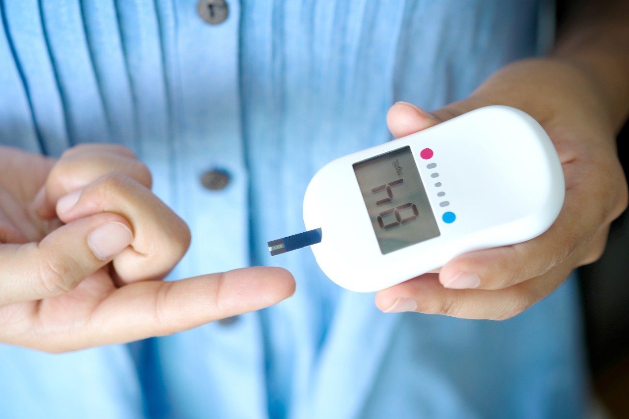 Person pricking their finger with a blood glucose monitor