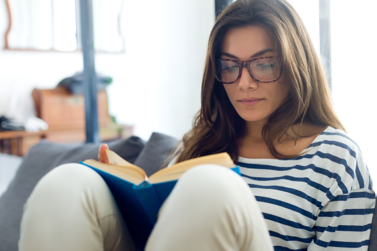 Woman sitting on a couch while reading a book