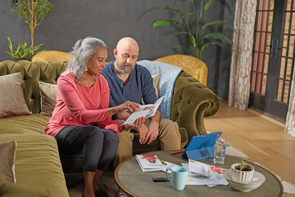 Man and woman sitting on a couch and reading through a brochure together