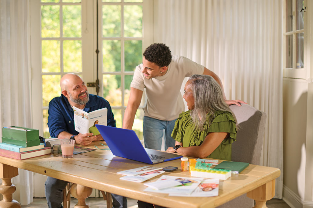 Young man speaking to his parents while they sit at a table reading the Staying on Track brochure