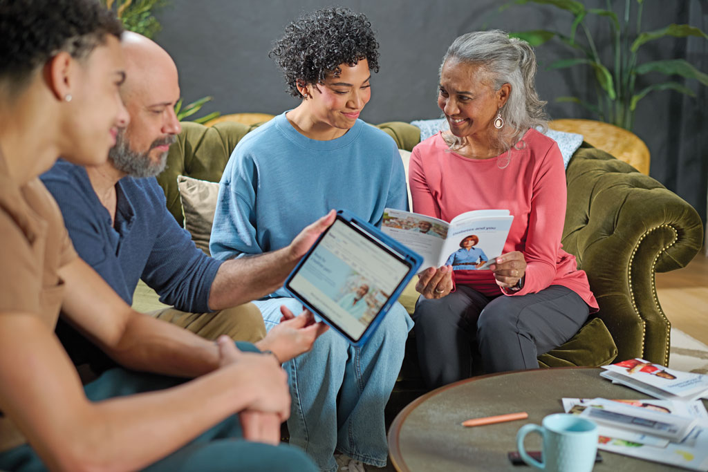Family of four sitting on a couch together and looking at a NovoCare® brochure and webpage 